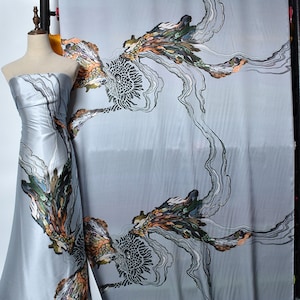 Könnte beinhalten: Grauer Satin-Stoff mit einem abstrakten floralen Druck in Schwarz und Weiß. Der Druck zeigt eine große Blume mit einem wirbelnden Muster und kleinere Blumen, die über den Stoff verteilt sind. Der Stoff ist glatt und seidig.