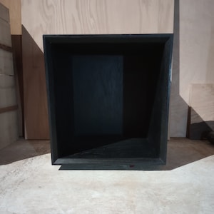 May include: A black wooden box with a square opening. The box is empty and has a smooth, polished finish.