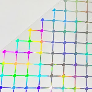 Könnte beinhalten: Eine Folie aus transparentem, selbstklebendem Vinyl mit einem holografischen Herzmuster. Die Herzen sind in einem Raster angeordnet und schimmern in verschiedenen Farben des Regenbogens.
