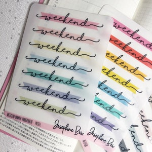 Könnte beinhalten: Transparente Aufkleber mit dem Wort "Wochenende" in Schreibschrift, jeweils auf einem pastellfarbenen Banner. Die Aufkleber sind auf einer Planerseite angeordnet. Der Text "Josephine Bow" ist ebenfalls sichtbar.