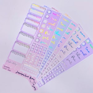 以下が含まれることがあります： 虹色のグリッターデザインのホログラフィックプランナー用ステッカー6枚セット。ステッカーには、ホログラフィックフォントで「月」「火」「水」「木」「金」「土」の曜日が書かれています。ステッカーは白い背景です。