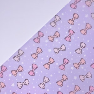 Könnte beinhalten: Ein lilafarbener Hintergrund mit einem sich wiederholenden Muster aus rosa und weißen Schleifen und weißen Sternen.