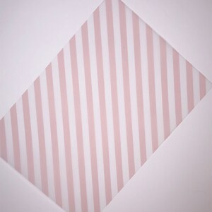 Könnte beinhalten: Ein weißer Hintergrund mit einer pinkfarbenen und weißen, gestreiften Diamantform in der Mitte.