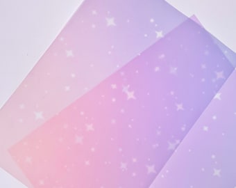Può includere: Tre fogli di carta traslucida con un gradiente dal rosa al viola e un motivo a stella bianca.