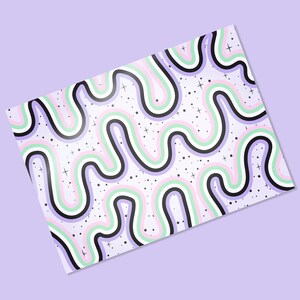May include: A patterned sheet with a repeating wavy design in black, white, light green, pink, and purple. Small black dots and white crosses are scattered across the white background. The sheet is angled on a light purple surface.