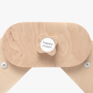 May include: A close-up of a wooden play structure with a knob that says "happy moon".