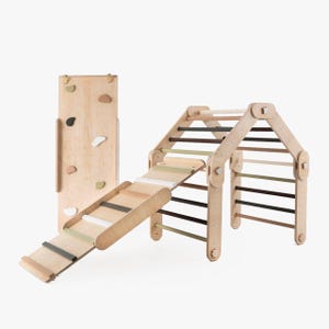 May include: A wooden climbing frame with a slide, a climbing wall, and a ladder. The frame is made of natural wood and has a light brown finish. The climbing wall has colorful handholds. The slide is made of wood and has a green and white striped design.