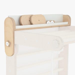 May include: A wooden climbing wall with a shelf on top. The shelf has two wooden circles and two white circles with the text "happy moon" on them. The climbing wall has a wooden knob with the text "happy moon" on it.