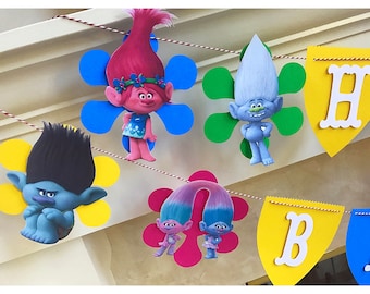May include: A colorful banner with Trolls characters, including Poppy, Branch, and Guy Diamond. The banner features the letters "Happy Birthday" in white on a yellow background.