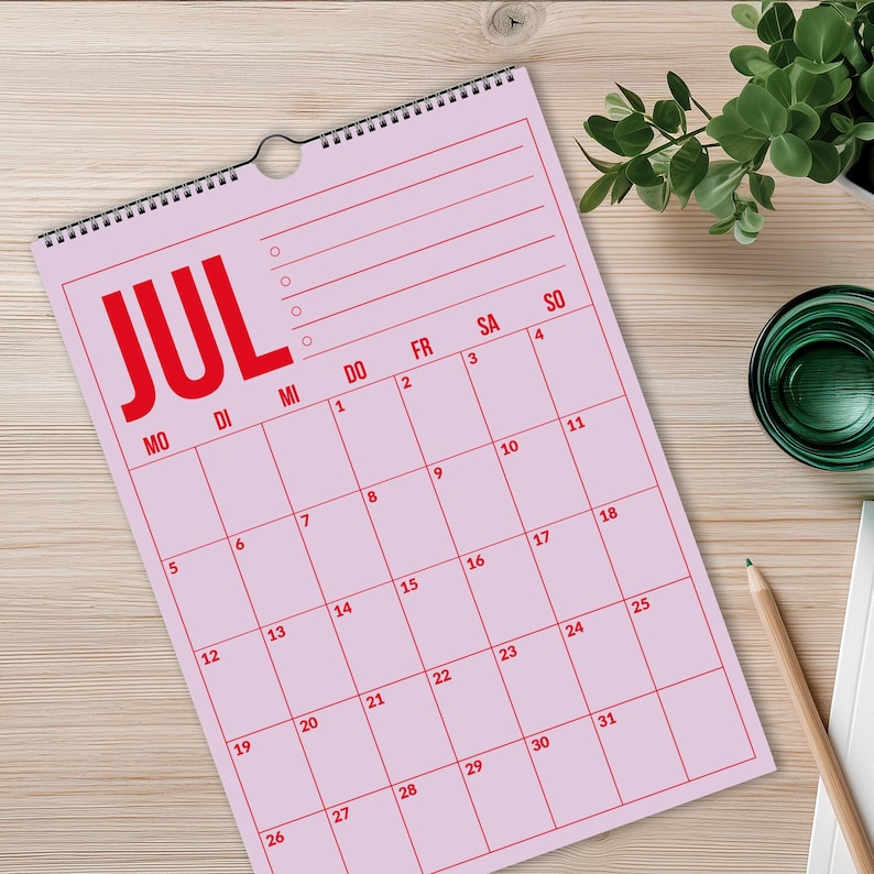 Pu&ograve; includere: Un calendario da parete rosa per luglio con testo rosso e linee a griglia. Il calendario mostra i giorni della settimana e le date numerate. La parola "JUL" &egrave; ben visibile in alto.
