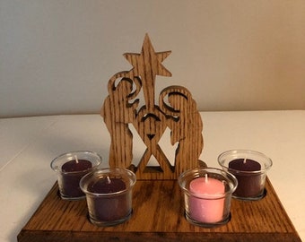 May include: Wooden nativity scene candle holder with four candle holders. The candle holders are filled with purple and pink candles. The nativity scene is made of wood and has a star on top.