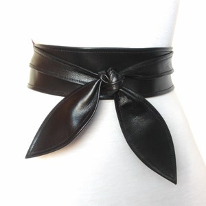 May include: A wide black leather belt with a long, pointed tie. The belt is tied in a knot at the front.