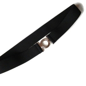Könnte beinhalten: Ein schwarzer Gummibandgürtel mit einer silbernen Ringschnalle.