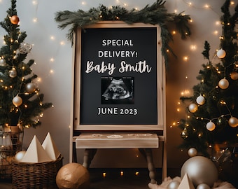 Op de afbeelding: Een krijtbord met de tekst "Special Delivery! Baby Smith" en een zwart-witte echografie. Het bord is versierd met een houten frame en staat op een houten ezel. Het bord is omringd door twee kleine kerstboompjes die versierd zijn met gouden en witte kerstballen.