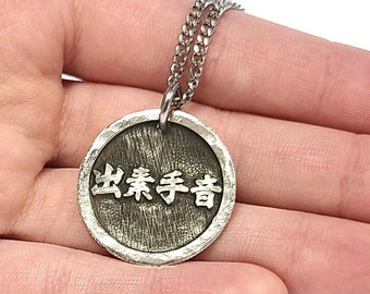 May include: A silver necklace with a round pendant featuring the Chinese characters "出类拔萃" (pronounced "chūlèibácuì") which translates to "outstanding" or "excellent".