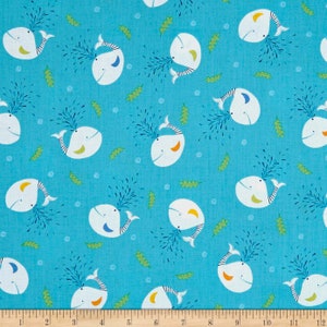 May include: A turquoise blue fabric with a repeating pattern of white whales blowing water. The whales have black eyes, black stripes, and orange and yellow accents.