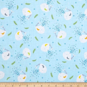 May include: A light blue fabric with a repeating pattern of white whales blowing blue water. The whales have yellow and gray accents. The background also has small blue dots and green leaves.
