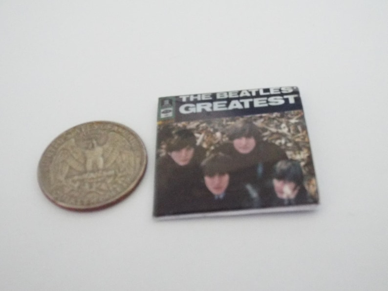 Może przedstawiać: Okładka winylowego albumu z epoki z czarno-białym zdjęciem The Beatles. Tytuł albumu to "The Beatles Greatest" w białym kolorze na czarnym tle.