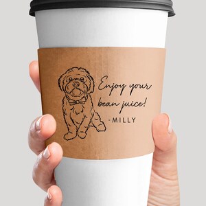 Może przedstawiać: Brązowy papierowy rękaw na kubek do kawy z czarno-białym rysunkiem psa w muszce. Tekst na rękawie brzmi "Enjoy your bean juice! - Milly"