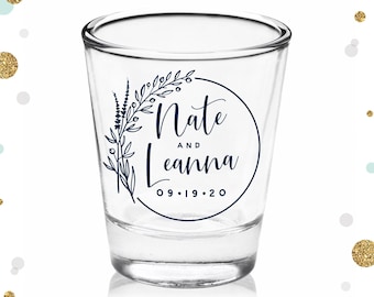 May include: A clear glass shot glass with a navy blue design featuring a floral motif and the text "Nate and Leanna 09.19.20".