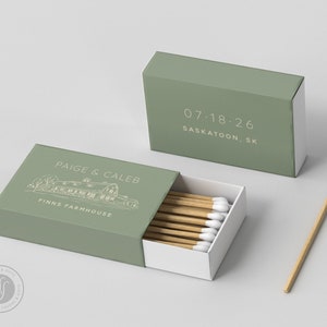 May include: Sage green matchboxes with white text and a line drawing of a house. One box is open, revealing wooden matches with white tips. The text on the box reads "PAIGE & CALEB FINNS FARMHOUSE" and "07.18.26 SASKATOON, SK".