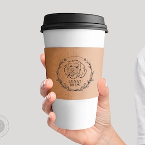 Puede incluir: Una funda de papel marrón para taza de café con una ilustración en blanco y negro de la cabeza de un perro dentro de una corona con el texto "Luna's Brew".