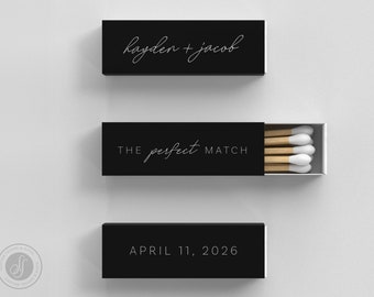 May include: Three black matchboxes with white text. The top box reads "hayden + jacob" in cursive. The middle box, partially open, says "THE perfect MATCH". The bottom box reads "APRIL 11, 2026".