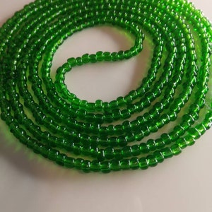 May include: A long strand of bright green glass beads. The beads are small and round, and they are strung together on a clear thread.