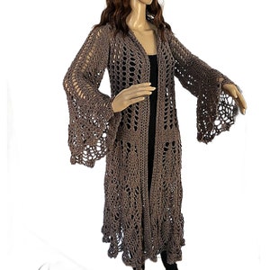 May include: A long, brown crochet cardigan with bell sleeves. The cardigan features a delicate openwork pattern and a flowing silhouette.