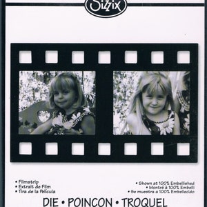 May include: Black die-cut filmstrip frame with two rectangular openings, each showing a black and white photo of a young girl. The Sizzix logo is at the top. Text includes "Filmstrip" and "Originals™ Large Grand Grande".