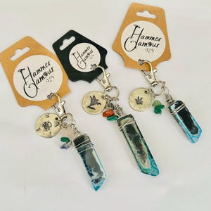 May include: Three keychains with blue and black crystal pendants, silver-tone hardware, and small charms. Each keychain has a tag with the text "Hammer Jamour 925". The charms include a compass, a bird, and a cannabis leaf.