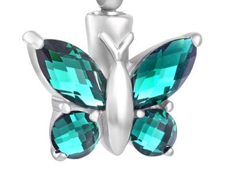 May include: Silver butterfly cremation necklace with green crystal accents. The necklace is a delicate chain with a pendant shaped like a butterfly with wings made of faceted green crystals.