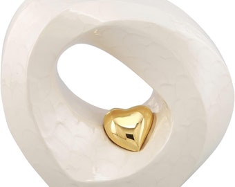 May include: White ceramic sculpture in the shape of a heart with a gold heart inside the opening.