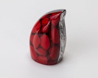 Op de afbeelding: Een klein, rood en zilveren decoratief beeldje in de vorm van een vogel. Het beeldje heeft een gedetailleerd, getextureerd oppervlak en een zilveren rand.