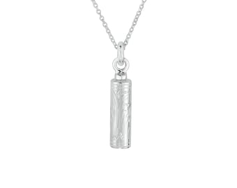 May include: A silver-colored pendant necklace featuring a cylindrical, engraved charm. The charm has a floral pattern and hangs from a delicate chain. The pendant is approximately 1 inch in length.