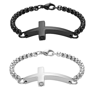 May include: Two cremation jewelry bracelets with a cross design. One bracelet is black and the other is silver.