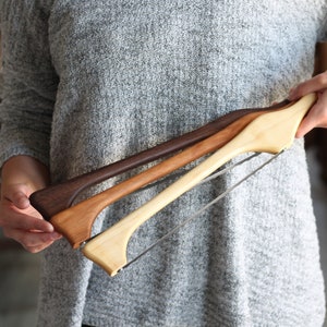 May include: Three wooden cake saws with a silver blade. The saws are made of different types of wood, including a dark brown wood, a light brown wood, and a natural wood.