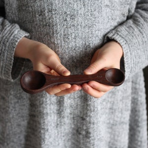 May include: A dark brown wooden measuring spoon with two sides, one marked "1 Tbsp" and the other marked "1/4 cup".