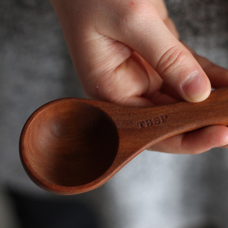 May include: A wooden tablespoon with the word "TBSP" engraved on the handle.