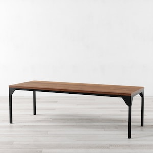 May include: A long, rectangular wooden table with a black metal frame. The table has a natural wood finish and a simple, modern design.