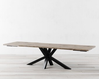 Puede incluir: Una mesa de comedor de madera larga y rectangular con un acabado de madera natural y una base de metal negro con un diseño de estrella. La mesa está sobre un suelo de madera clara.