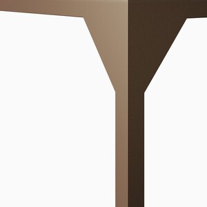 May include: Close-up of a table leg made of metal with a brown finish. The leg has a Y-shaped design.