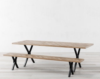 May include: A light brown wooden dining table and bench set. The table and bench have a herringbone pattern and are supported by black metal legs. The table is rectangular, and the bench is a similar design.