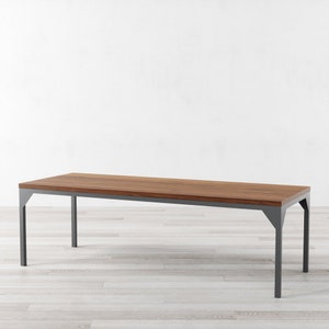 May include: A long, rectangular dining table with a dark wood top and a gray metal frame. The table has a simple, modern design.