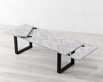 May include: A white wooden dining table with a chevron pattern and black metal legs. The table has two leaves that can be extended to increase the table's length.