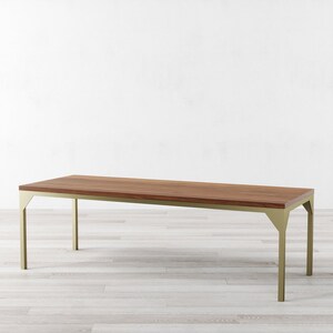 May include: A long, rectangular dining table with a brown wood top and a gold metal frame. The table has a simple, modern design.