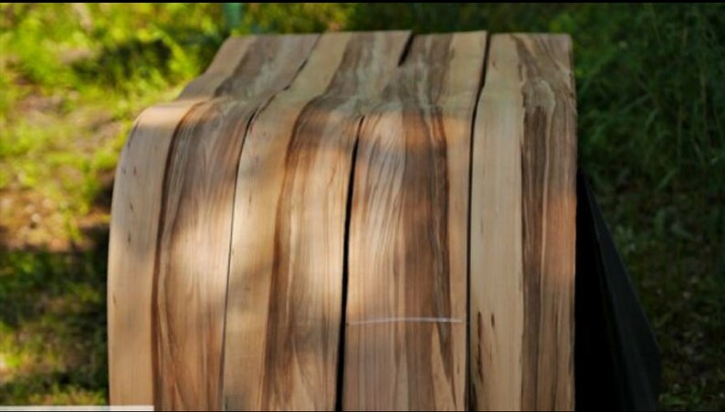 Puede incluir: Primer plano de un conjunto de chapas de madera, cada una con un patr&oacute;n de veta &uacute;nico. Las tiras est&aacute;n dispuestas en forma curva, mostrando la belleza natural de la madera.