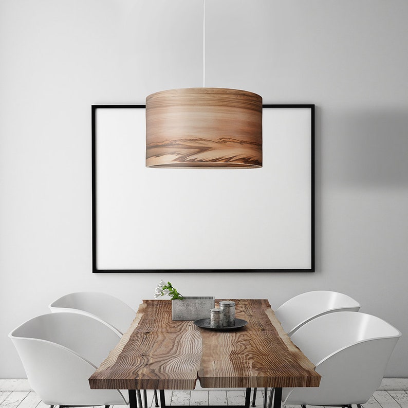Puede incluir: Una l&aacute;mpara colgante de madera con un acabado de veta de madera natural cuelga sobre una mesa de madera con cuatro sillas blancas. La mesa tiene un dise&ntilde;o de borde vivo y est&aacute; hecha de madera recuperada.