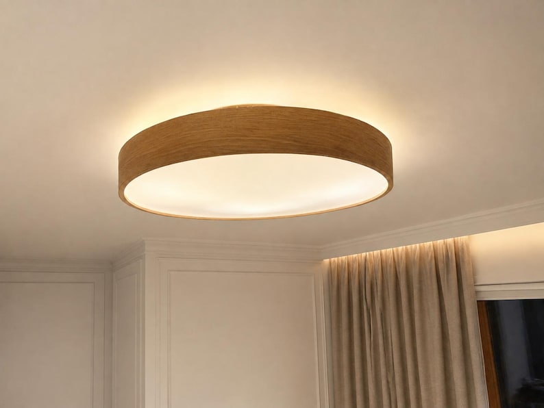 May include: A circular flush mount ceiling light fixture featuring a light brown wood grain frame and a flat, white circular diffuser that emits a soft, warm glow across the ceiling surface, creating a clean and simple lighting solution.