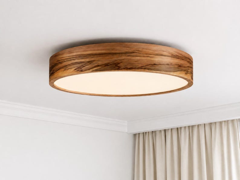 May include: A circular flush mount ceiling light fixture featuring a natural wood grain frame with a warm brown finish and a flat, opaque white diffuser panel that emits a soft, even glow across the surface of the light fixture.